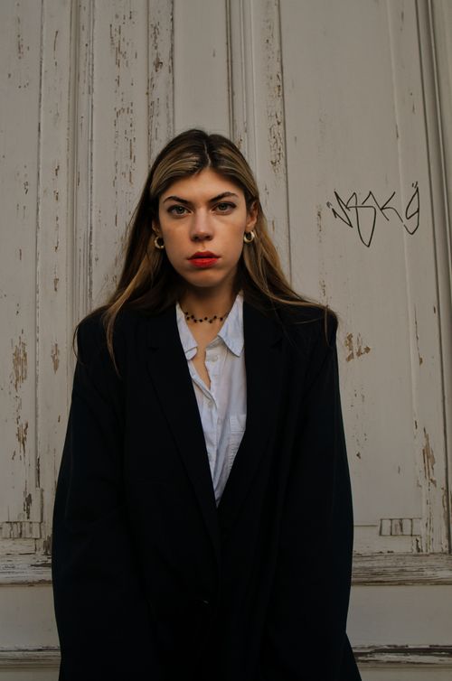 Free Stylish woman in a black blazer posing against a rustic door. Stock Photo