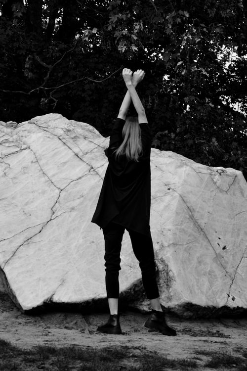 Free Stylish individual striking a pose against a large rock in Berlin. Unique fashion statement. Stock Photo