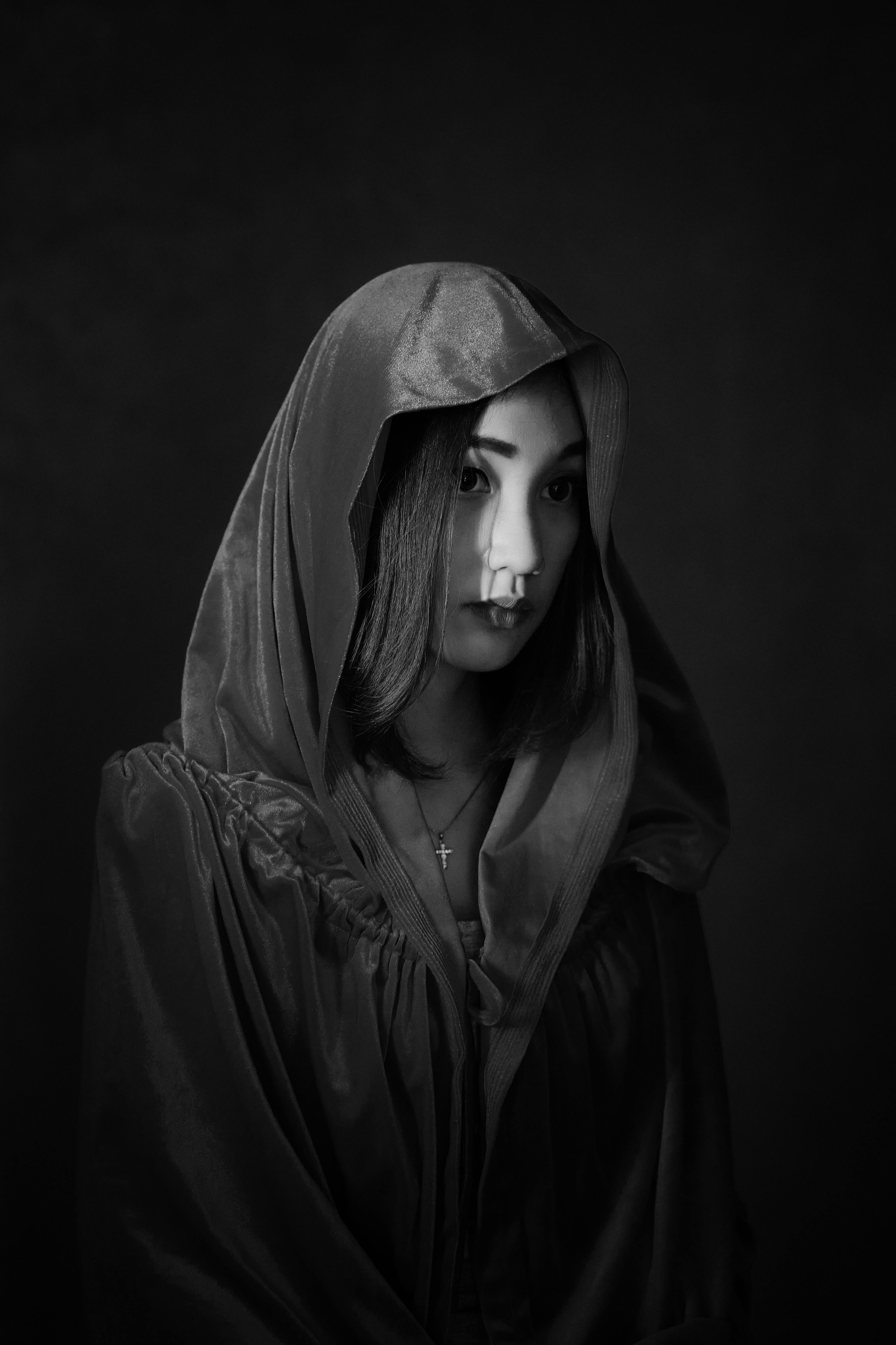 무료 후드 달린 망토를 두른 여인의 흑백 초상화로, 신비롭고 우아한 분위기를 자아낸다. 스톡 사진