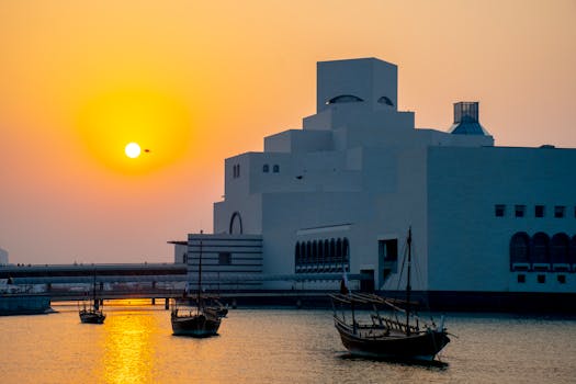 Stunning sunset at the Museum of Islamic Art in Doha, Qatar with traditional boats on the water.