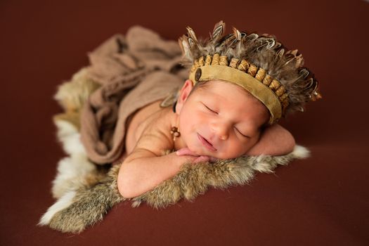 Sweet newborn baby peacefully sleeping in a cute feather headband and soft wrap.