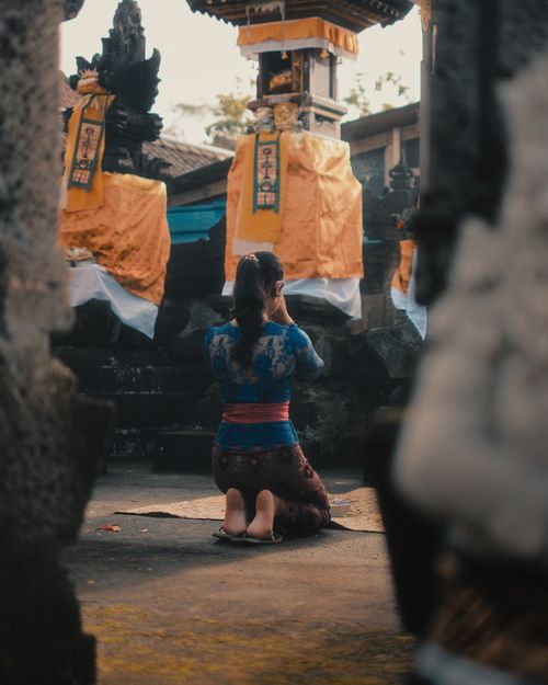 Free A woman in traditional attire prays at a Balinese temple, capturing cultural essence. Stock Photo
