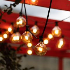 Warm round festoon bulbs hanging under a red awning
