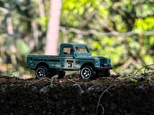 Free A green toy truck rests on a moss-covered rustic surface amidst a lush outdoor setting. Stock Photo