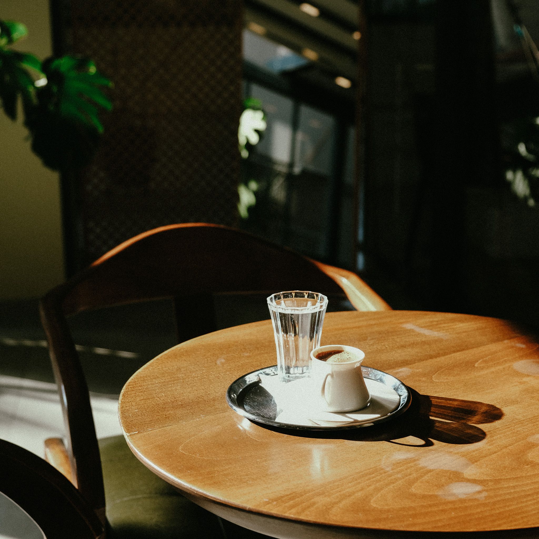 A warm, sunlit cafe table featuring Turkish coffee and water, captured indoors.