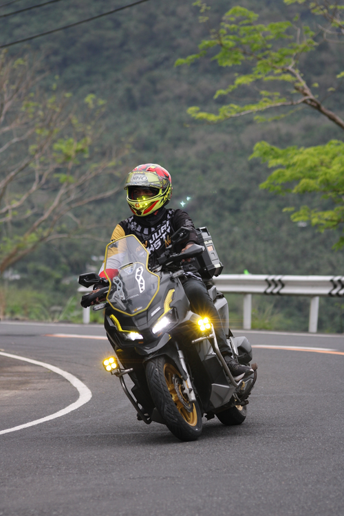 Free A biker skillfully rides a motorcycle on a winding road with lush green surroundings. Stock Photo