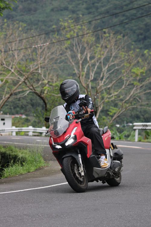 Free A motorcyclist cornering on a curvy mountain road with lush greenery and trees providing a scenic backdrop. Stock Photo