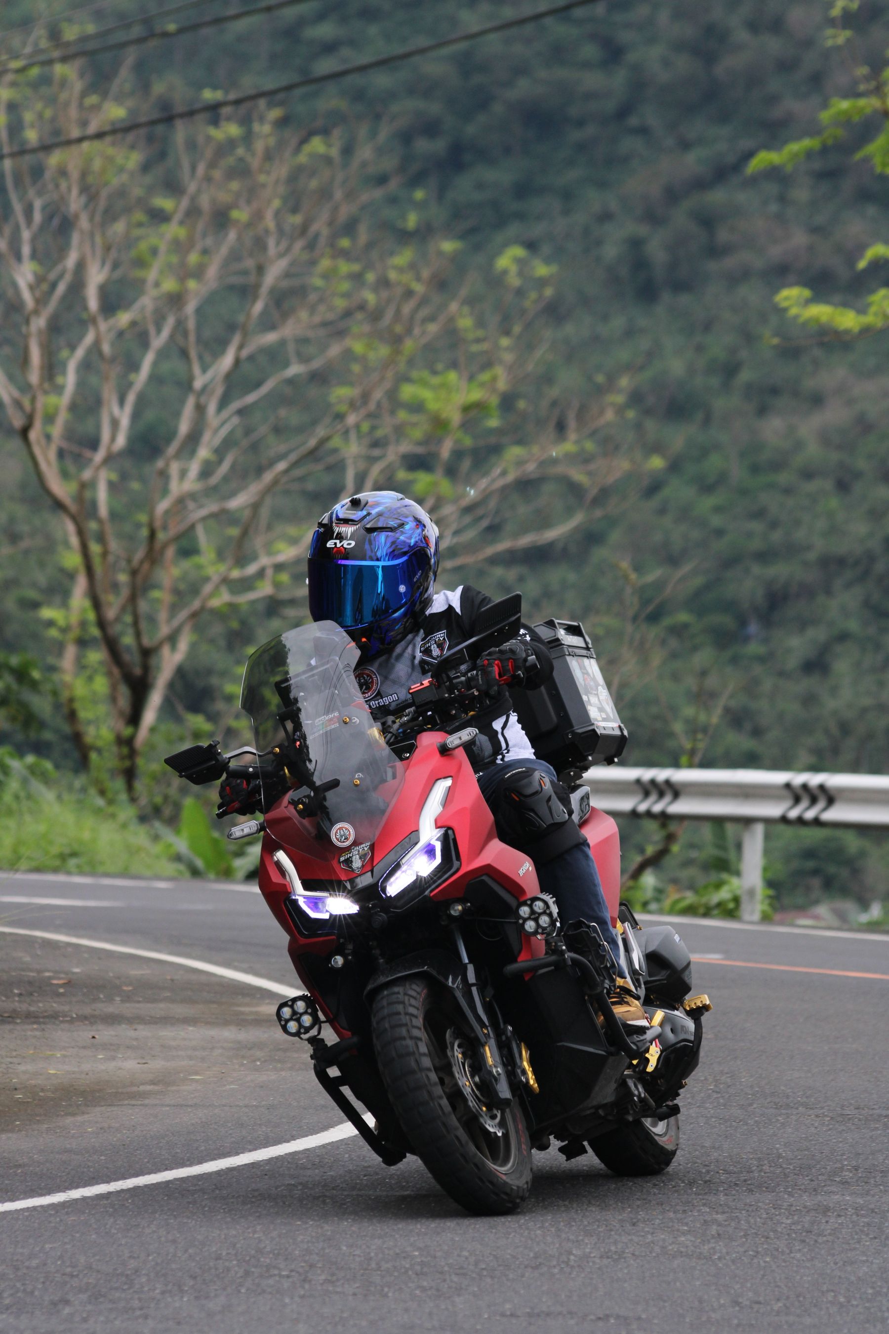 Helmeted motorcycle rider traveling on a winding road with touring equipment