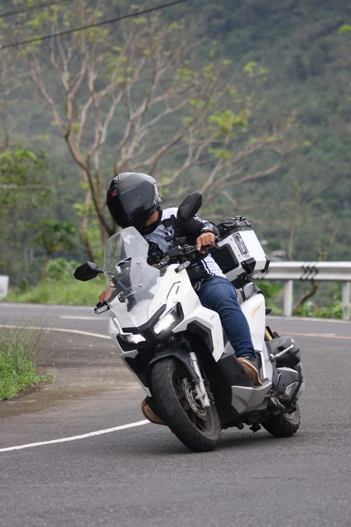 Free Motorcyclist navigating a sharp turn on a scenic mountain road, showcasing thrilling adventure. Stock Photo