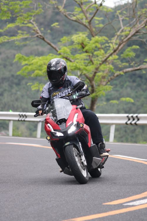 Free A motorcyclist wearing safety gear rides down a winding mountain road, showcasing adventure and freedom. Stock Photo