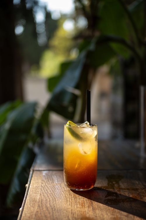 Free A vibrant iced cocktail with citrus garnish sits on a wooden table outdoors. Stock Photo
