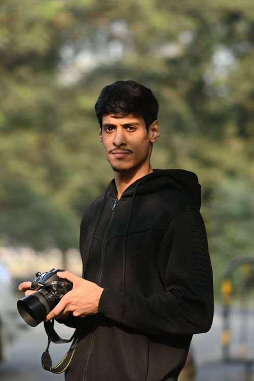 Free Portrait of a young male photographer holding a camera outdoors in Kolkata, India. Stock Photo