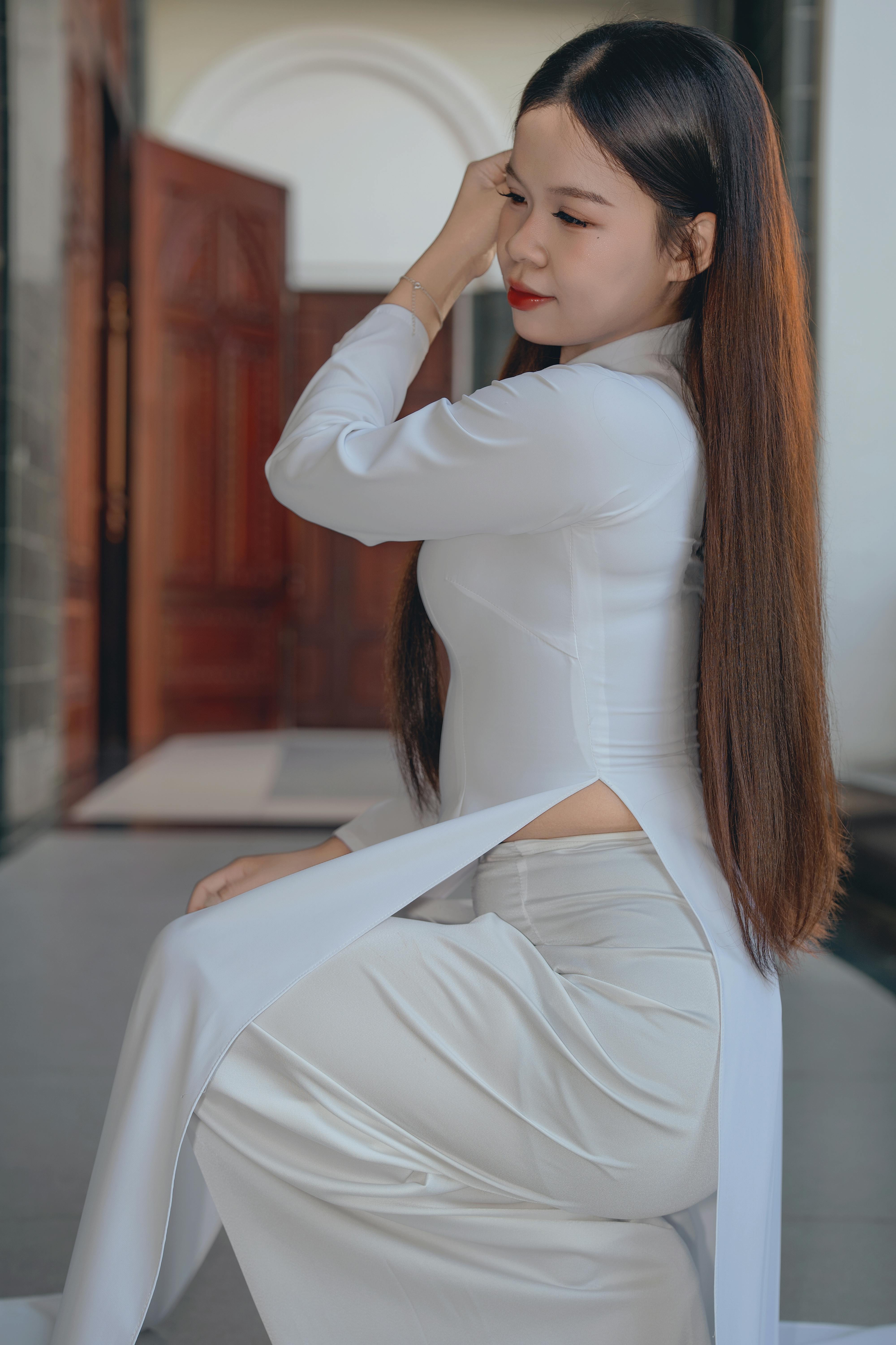 Portrait of a woman in traditional white attire with long hair, captured indoors.
