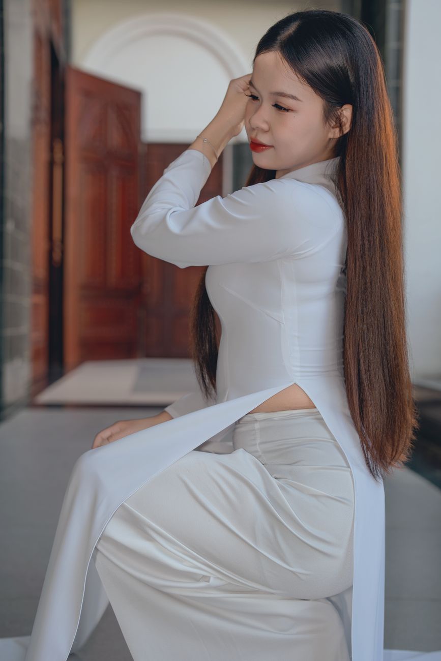 Portrait of a woman in traditional white attire with long hair, captured indoors.