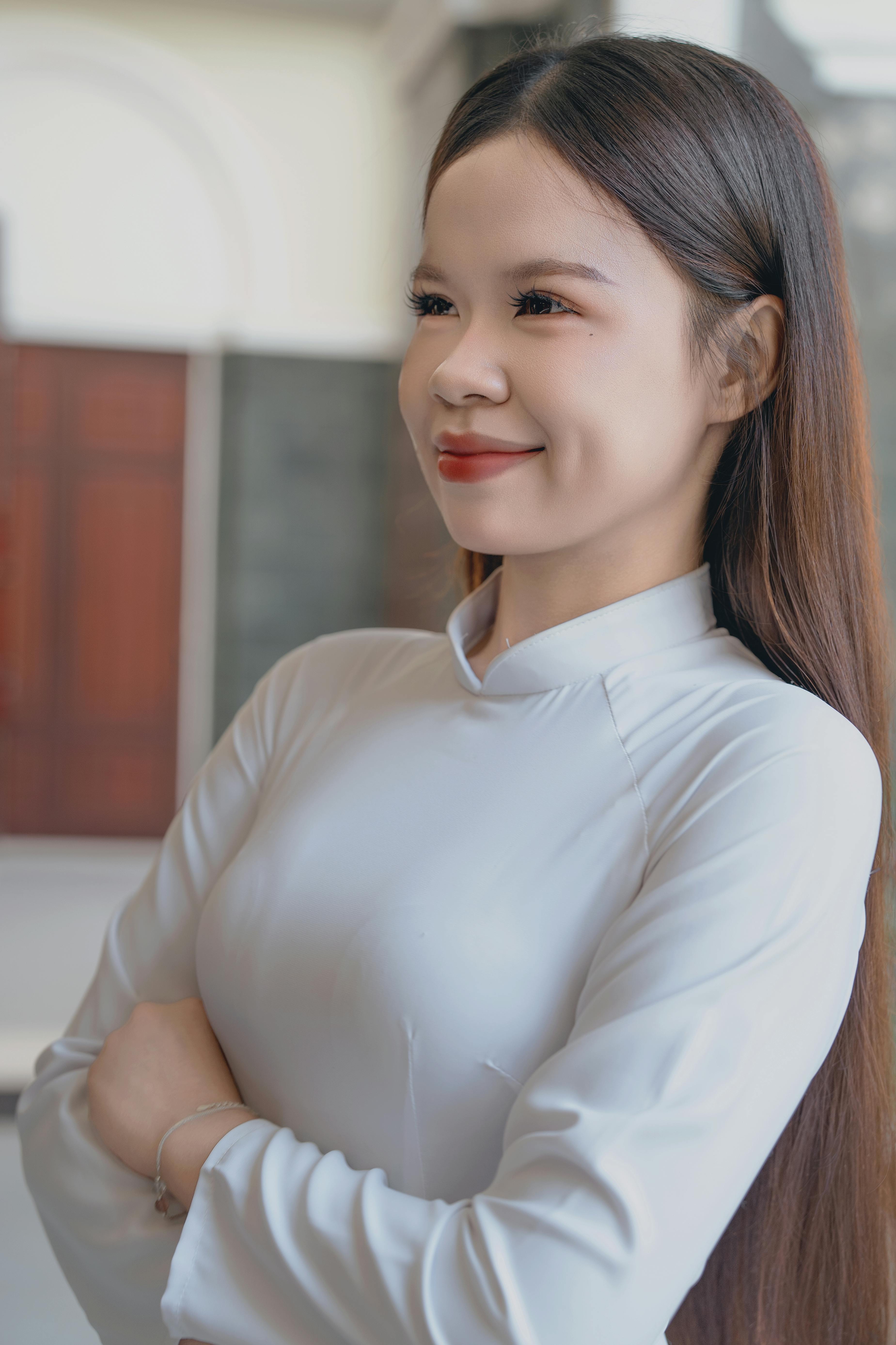 Ilmainen Nuori nainen perinteisessä asussa hymyilee itsevarmasti kädet ristissä ulkona. Kuvapankkikuva