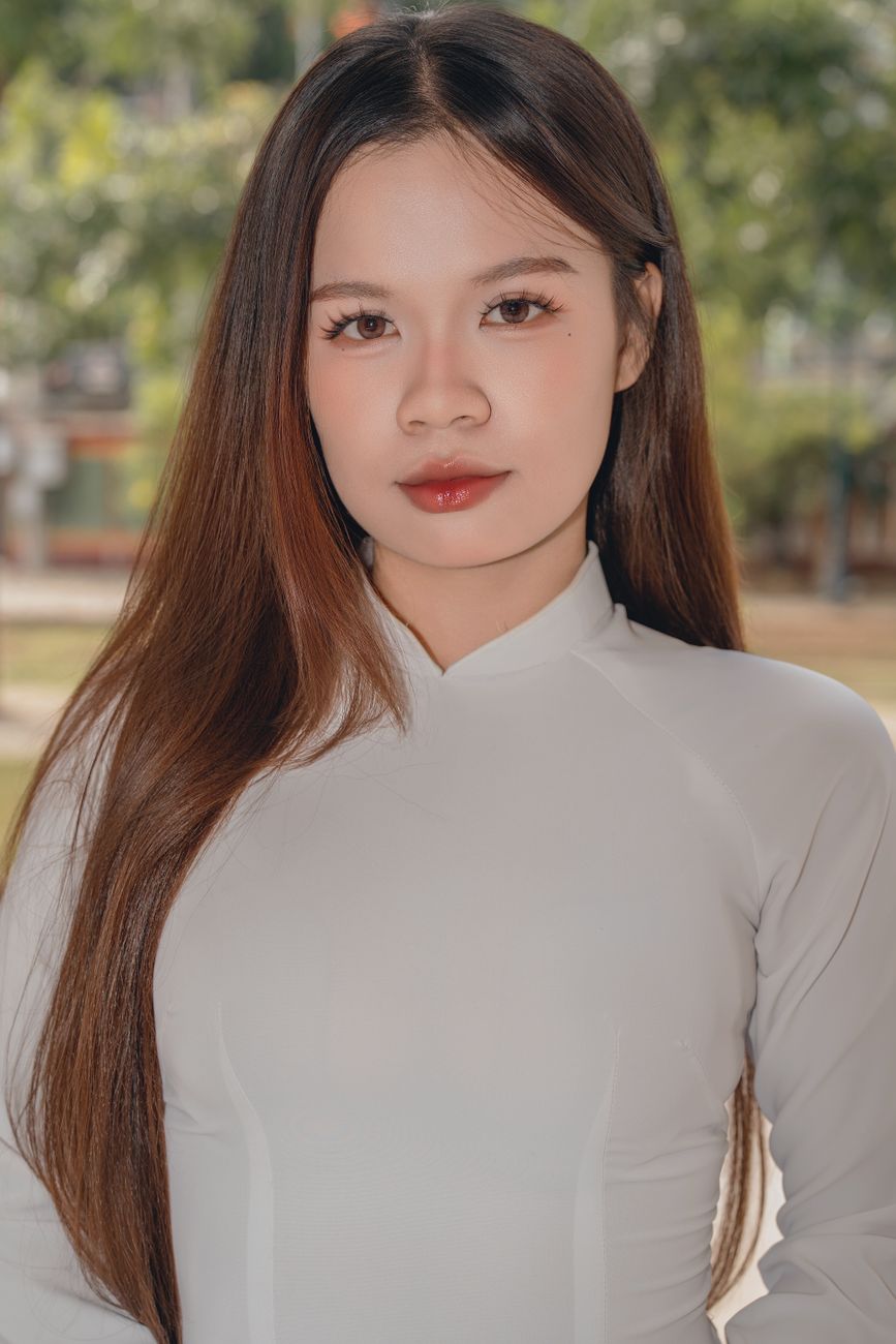 Young woman wearing traditional clothing posing outdoors, looking at the camera.