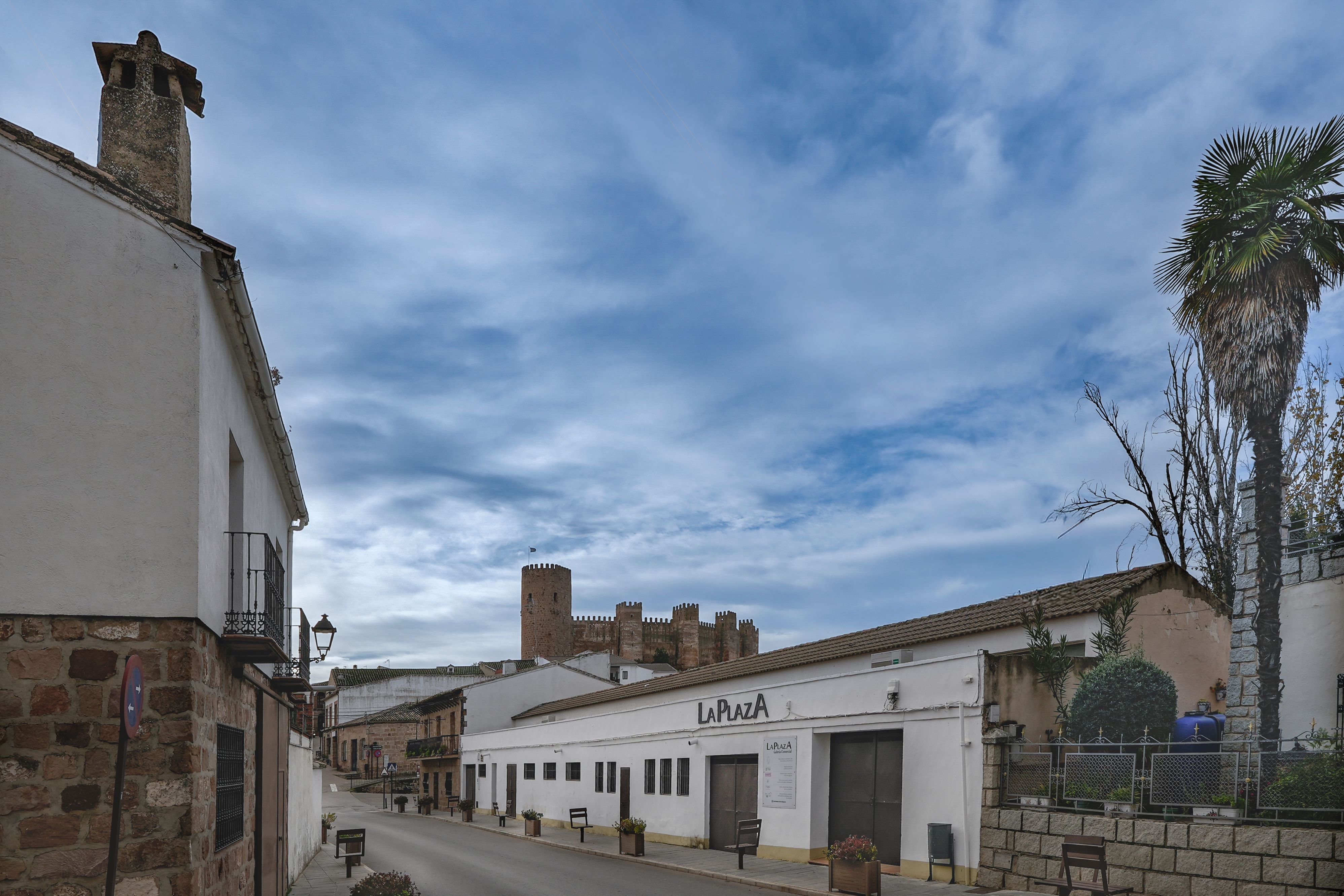 Charming street view in Baños de la Encina, featuring historic architecture and vibrant blue skies.