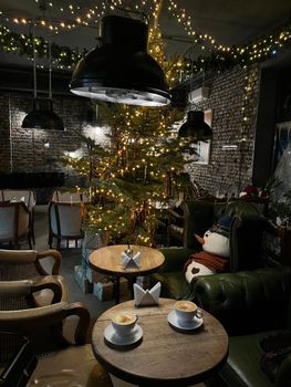 Warm cafe with Christmas decor, featuring cappuccinos and festive lighting.