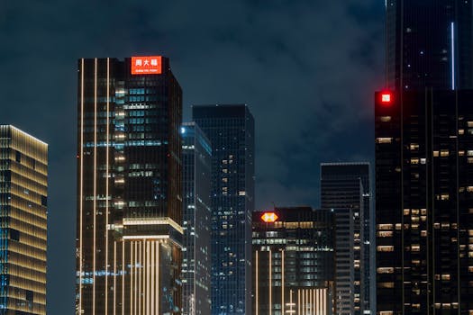Night view of illuminated skyscrapers in a modern city skyline.