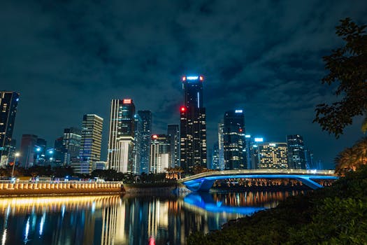 A stunning night view of a modern city with illuminated skyscrapers and a reflection in the river.