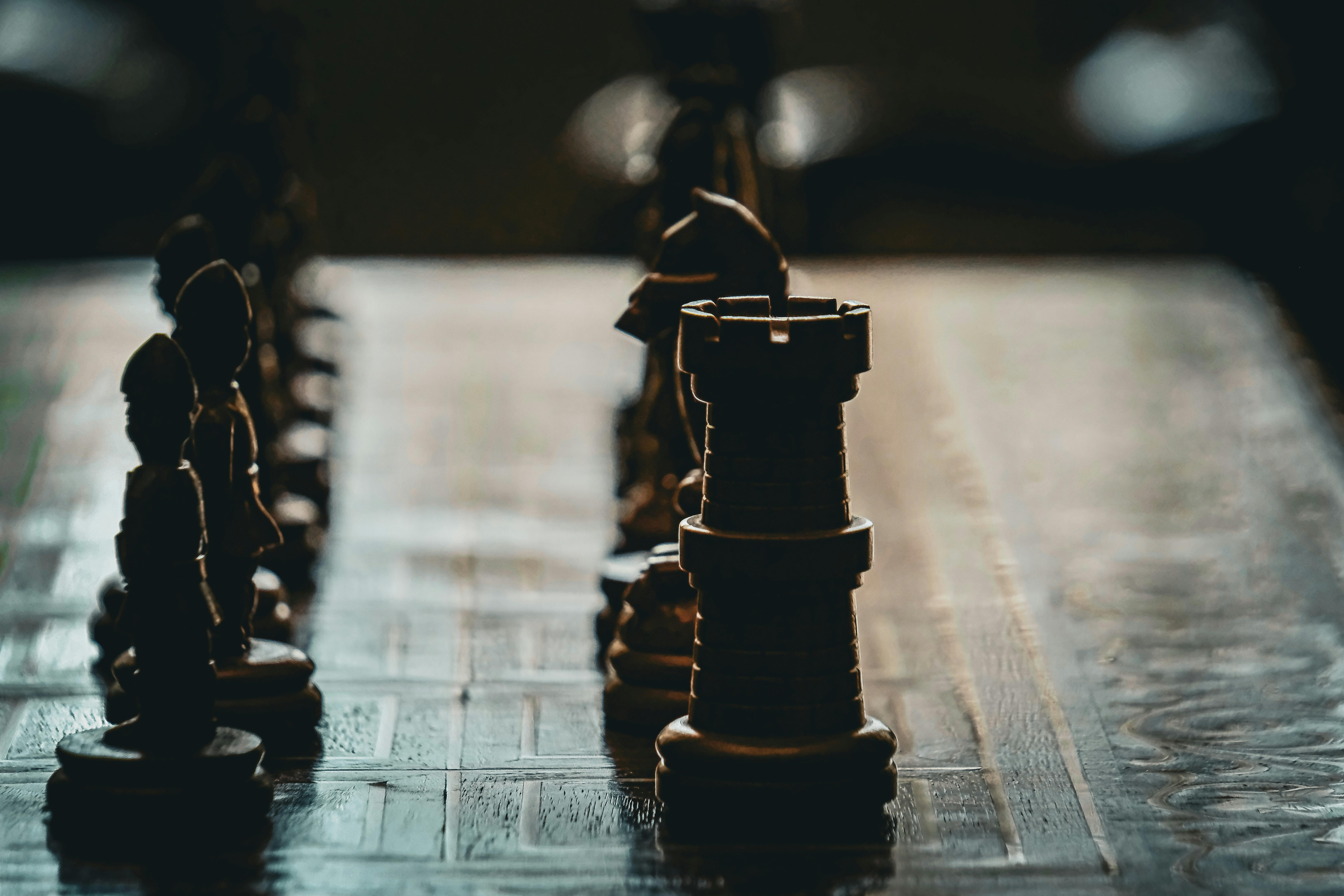Close-up of a chess board with dramatic lighting and focus on a rook piece.