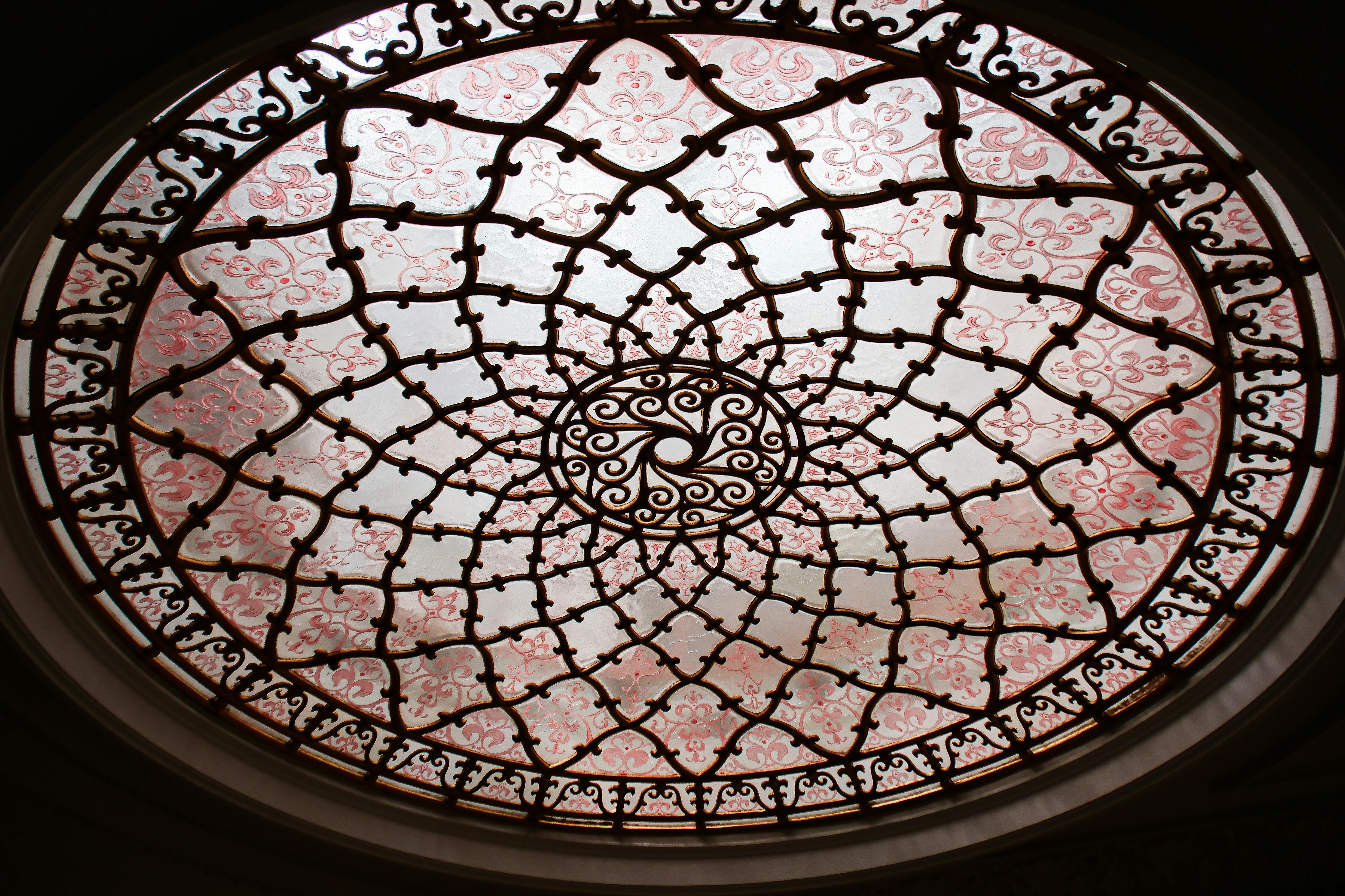 A detailed view of an ornate stained glass dome ceiling with intricate patterns and metal framework.