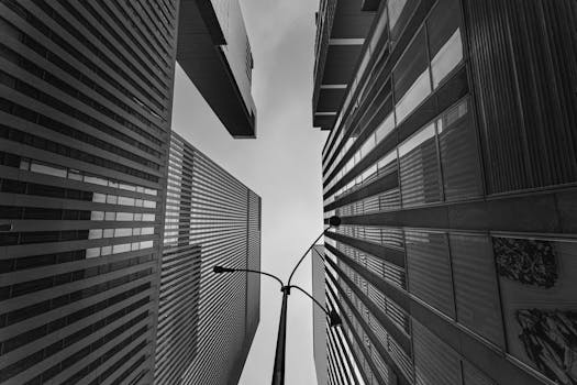 Black and white view of skyscrapers and a street lamp in New York City viewed from below.
