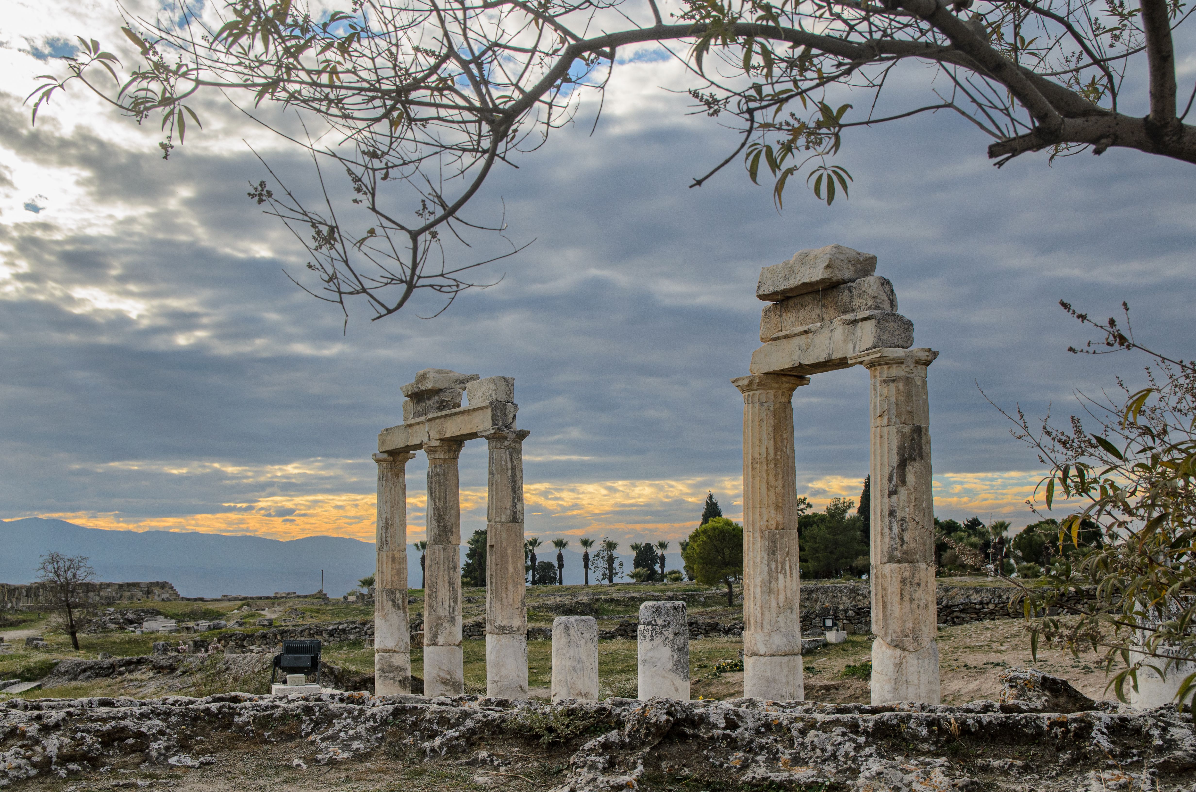 Beautiful view of ancient ruins in Pamukkale, Denizli, Türkiye with a dramatic sky at dusk.