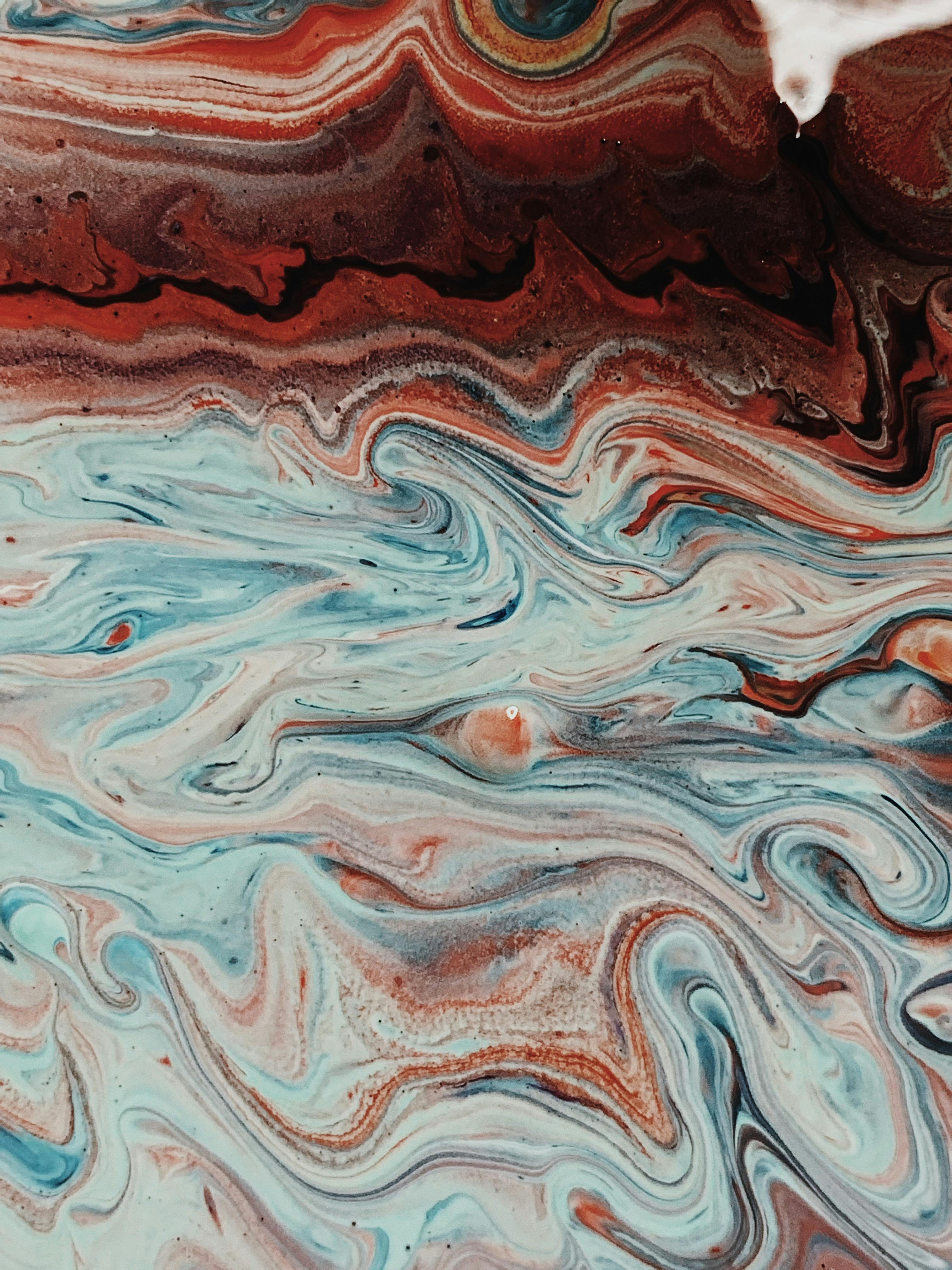 Abstract fluid artwork with vibrant blue and earthy red tones creating a mesmerizing swirl pattern.