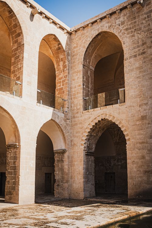 Free Detailed view of historic stone architecture featuring arched walkways and sunlight. Stock Photo