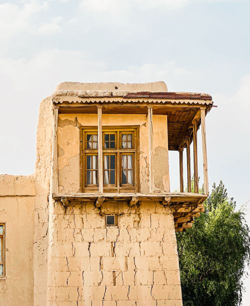 Free Rustic mud brick house with wooden balcony in a sunny setting. Stock Photo