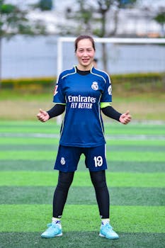 A female soccer player smiling confidently on a field in Hanoi, Vietnam.