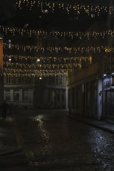 Cobblestone street adorned with festive string lights at night, creating a warm, inviting atmosphere.