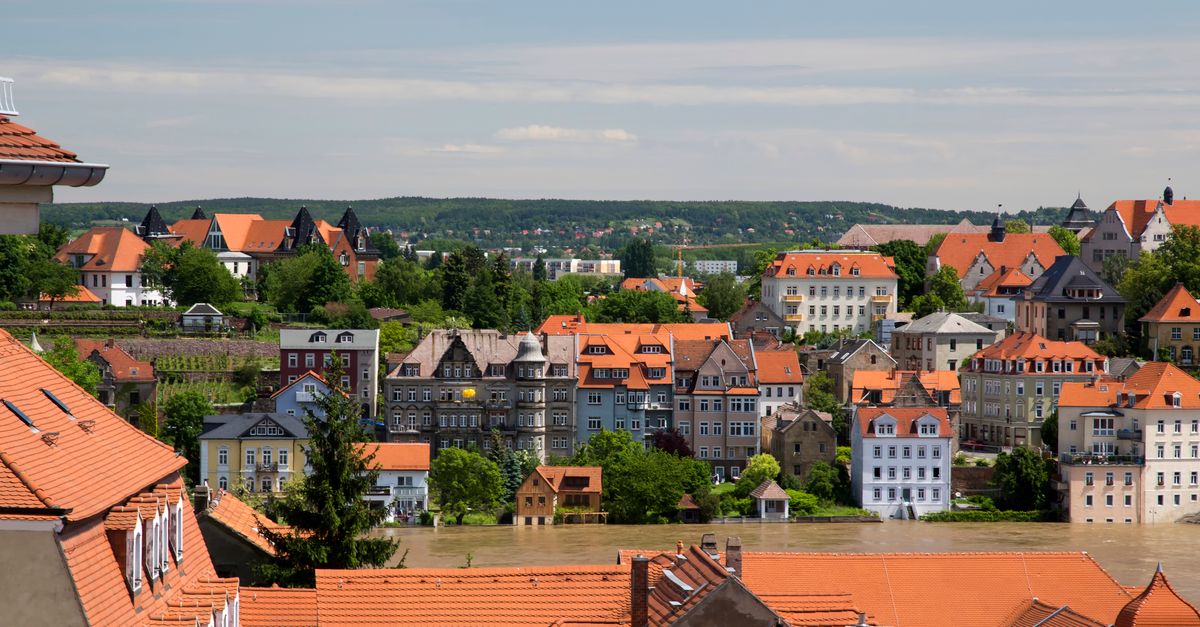 Aerial view of picturesque European town with orange rooftops and lush greenery.