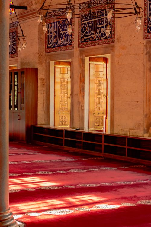 Free Serene mosque interior featuring ornate calligraphy and soft sunlight streaming through windows. Stock Photo