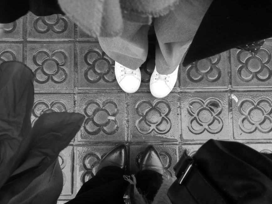 Stylish footwear on iconic modernist tiles in Barcelona streetscape from above.