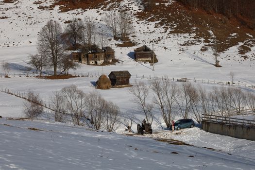 Scenic winter landscape featuring snow-covered rural farms and houses in a mountainous region.