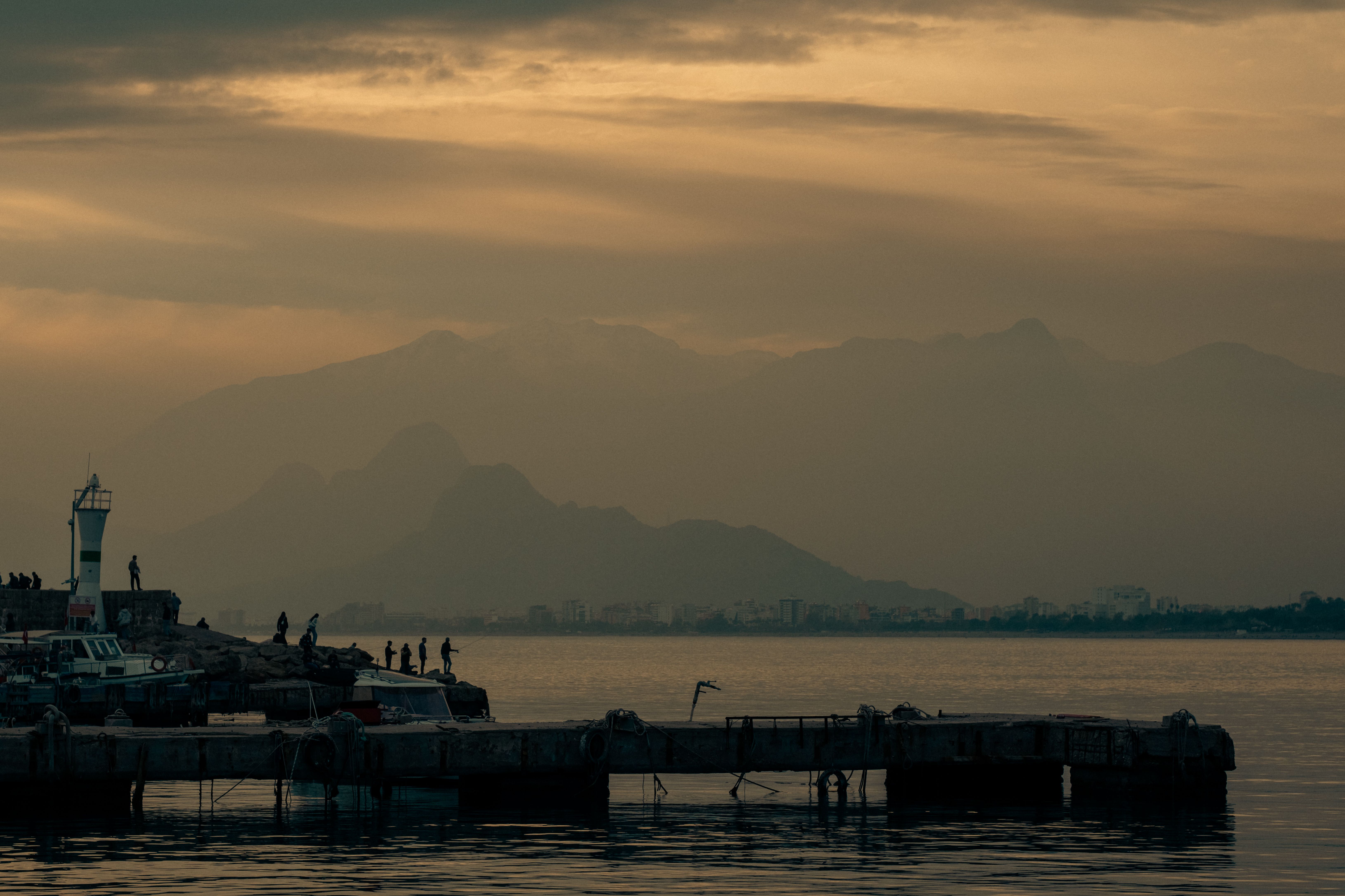 small Albanian coastal town pier at sunset with local fishermen