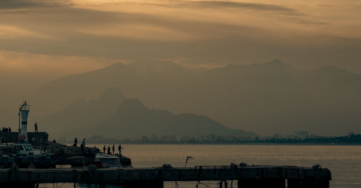small Albanian coastal town pier at sunset with local fishermen