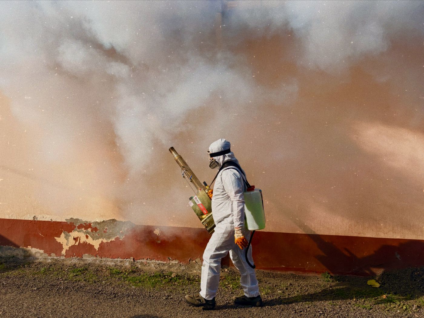 Licensed pest control technician in protective gear treating a property