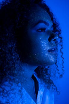 在忧郁的蓝色灯光下，拍摄了一位脸上有闪光的年轻女子的侧面肖像