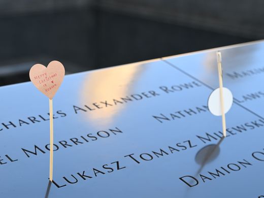 Emotional tribute with a heart card at a memorial displaying engraved names.