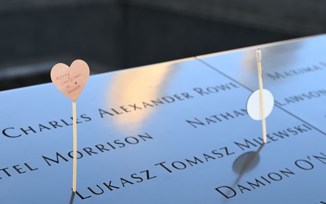Photo: Victor Zhang on Pexels Emotional tribute with a heart card at a memorial displaying engraved names.