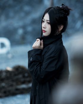 Thoughtful woman with dark hair in black coat outdoors, capturing a pensive mood.
