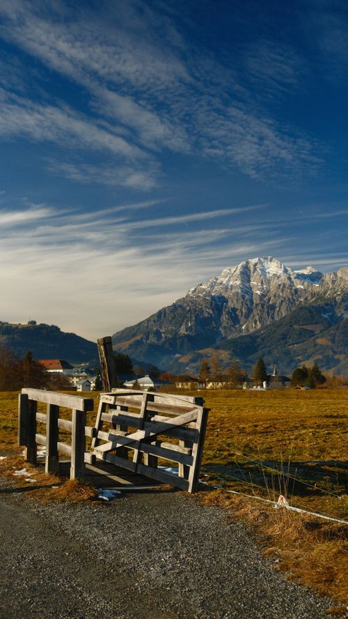Free Rustic wooden fence overlooking snow-capped Alpine mountains during winter day. Stock Photo