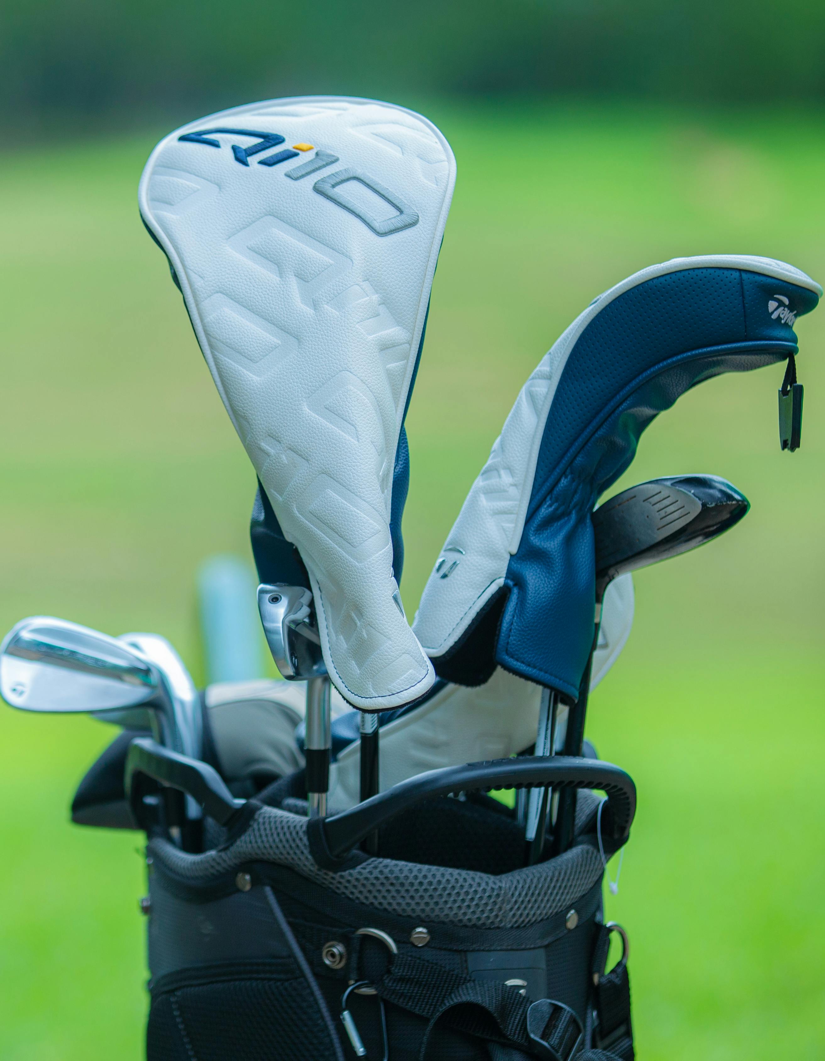 Close-up of a golf club set in a carry bag featuring head covers on a green golf course.