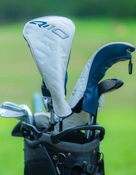 Close-up of a golf club set in a carry bag featuring head covers on a green golf course.