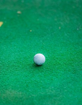 A close-up view of a golf ball resting on green turf, emphasizing sports equipment.