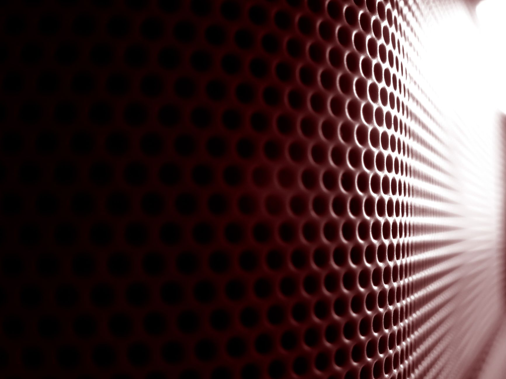 Close-up view of a perforated surface with abstract design elements and a gradient of light.