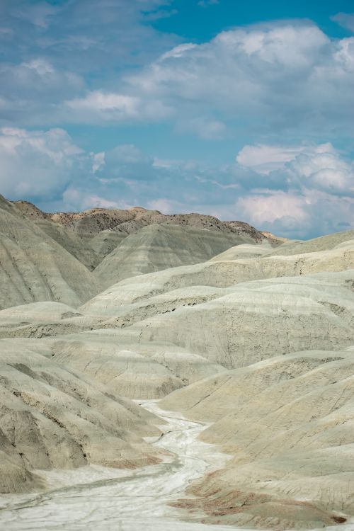 Free Stunning view of eroded hills under a vibrant blue sky with clouds. Stock Photo